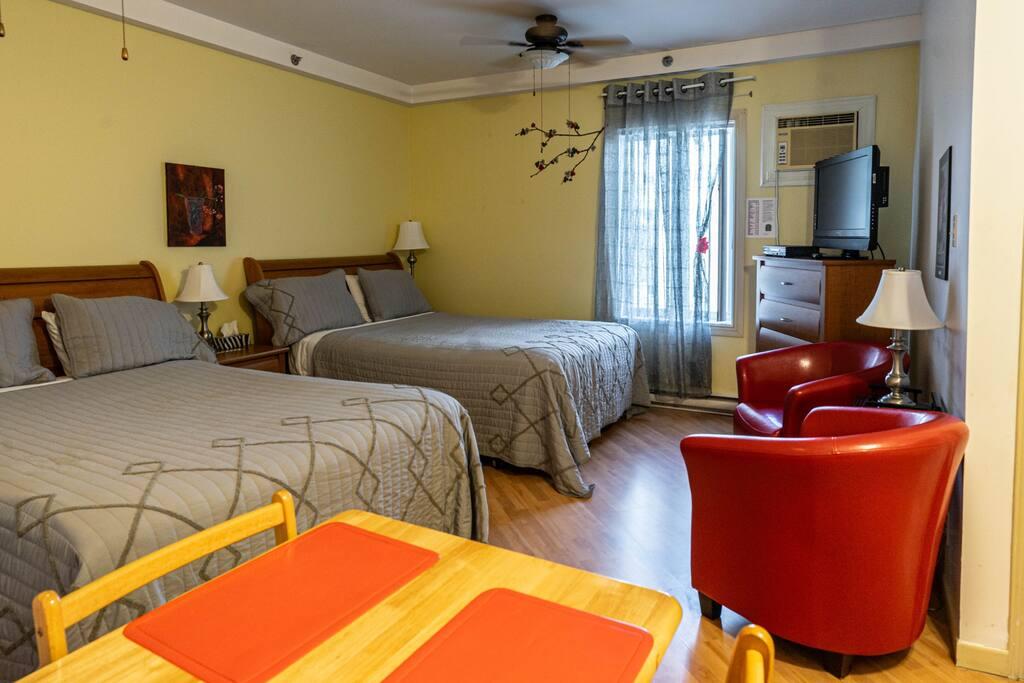 Room with carved mahogany furniture, a bed with a burgundy patterned bedspread and a suede armchair by the window