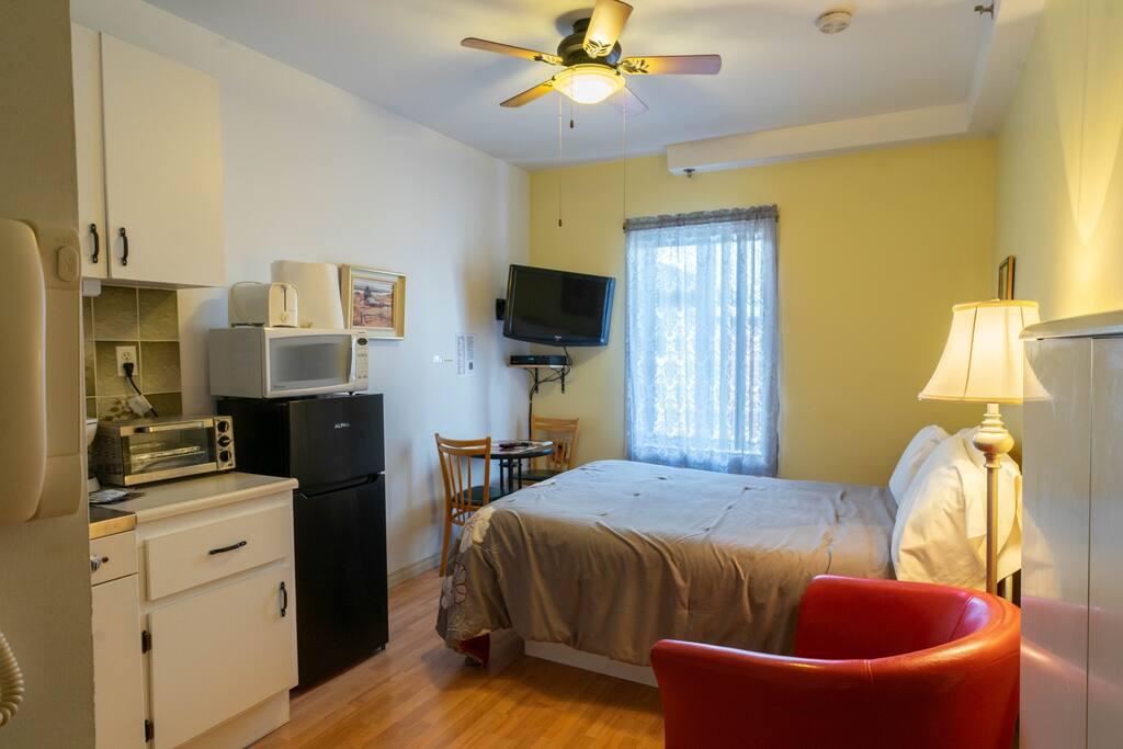 Yellow room with a compact kitchenette, a black mini-fridge and a red leather armchair