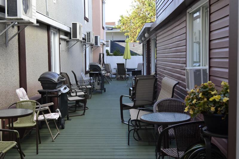 Terrasse extérieure commune de l'auberge avec barbecues, mobilier de patio et climatiseurs muraux