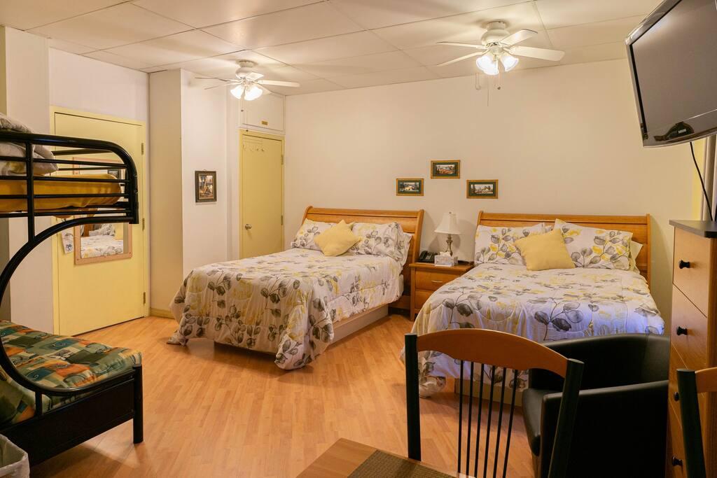 Chambre familiale avec lits capitaine en bois, couchette superposée et literie à motifs floraux jaune et gris